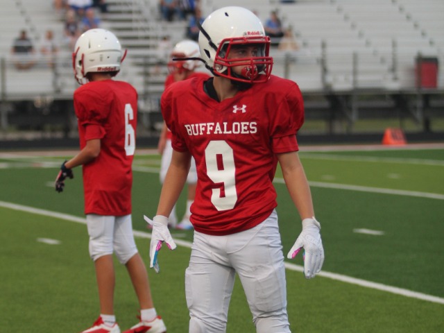 An LOMS football player wearing a red nuumber 9 jersey turns away from the camera between plays