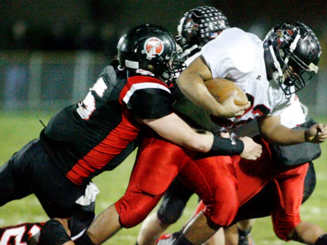 Loren Snow (22) of West Carrollton is tackled by Zeke Eier (5) and Kyle Sanning (20) of Tecumseh during Friday's first-round Division II playoff footb