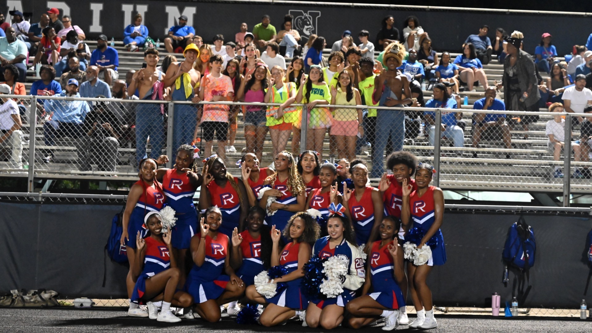 Varsity Cheer poses with the TRIBE (PRHS Student Section) holding their “B,” symbolizing Big Blue.