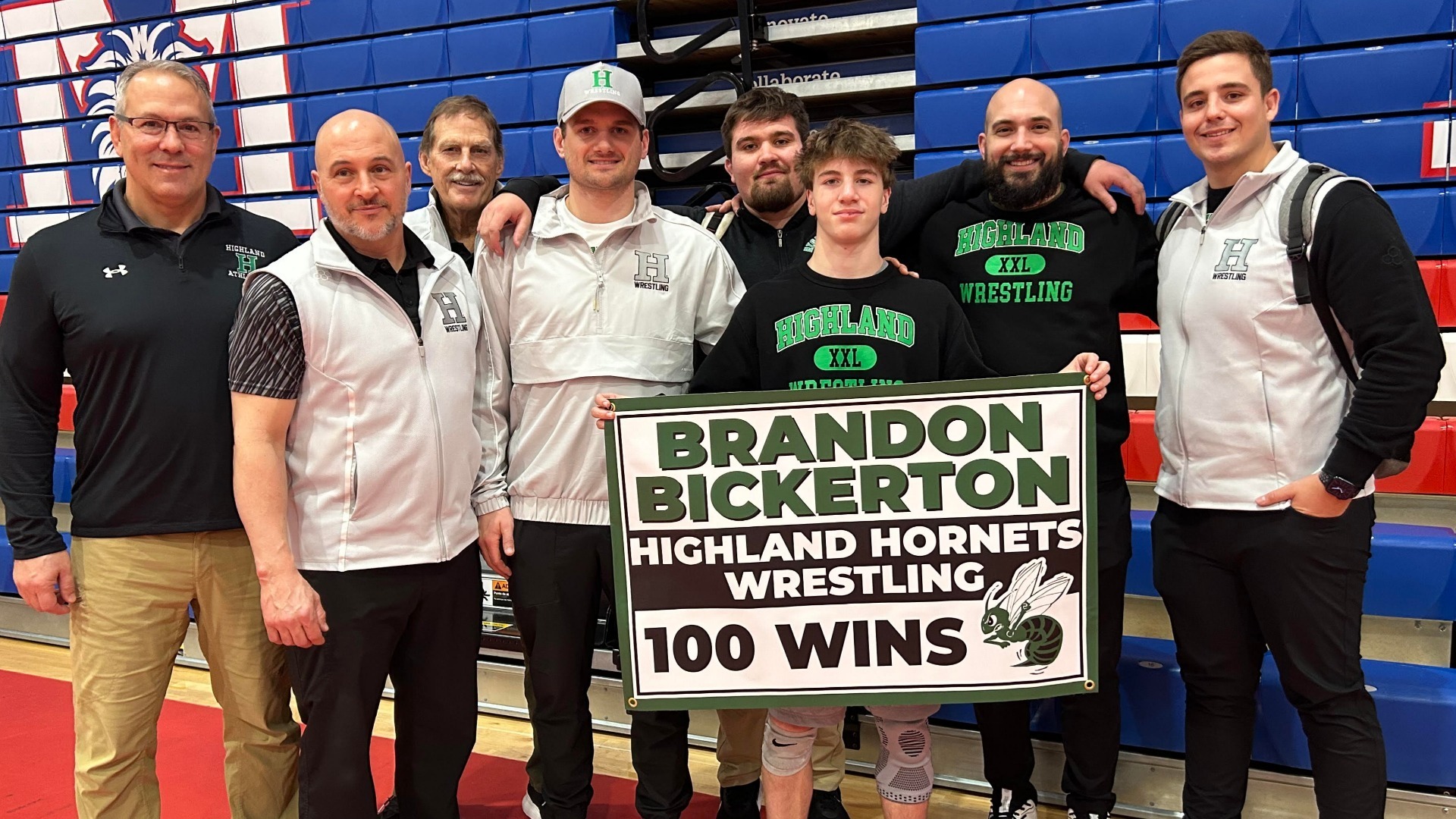 Brandon standing with his coaches and his 100 win banner